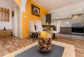 A modern kitchen with white cabinets, a dining area with a table and chairs, and a decorative glass vase with dried flowers on a table.