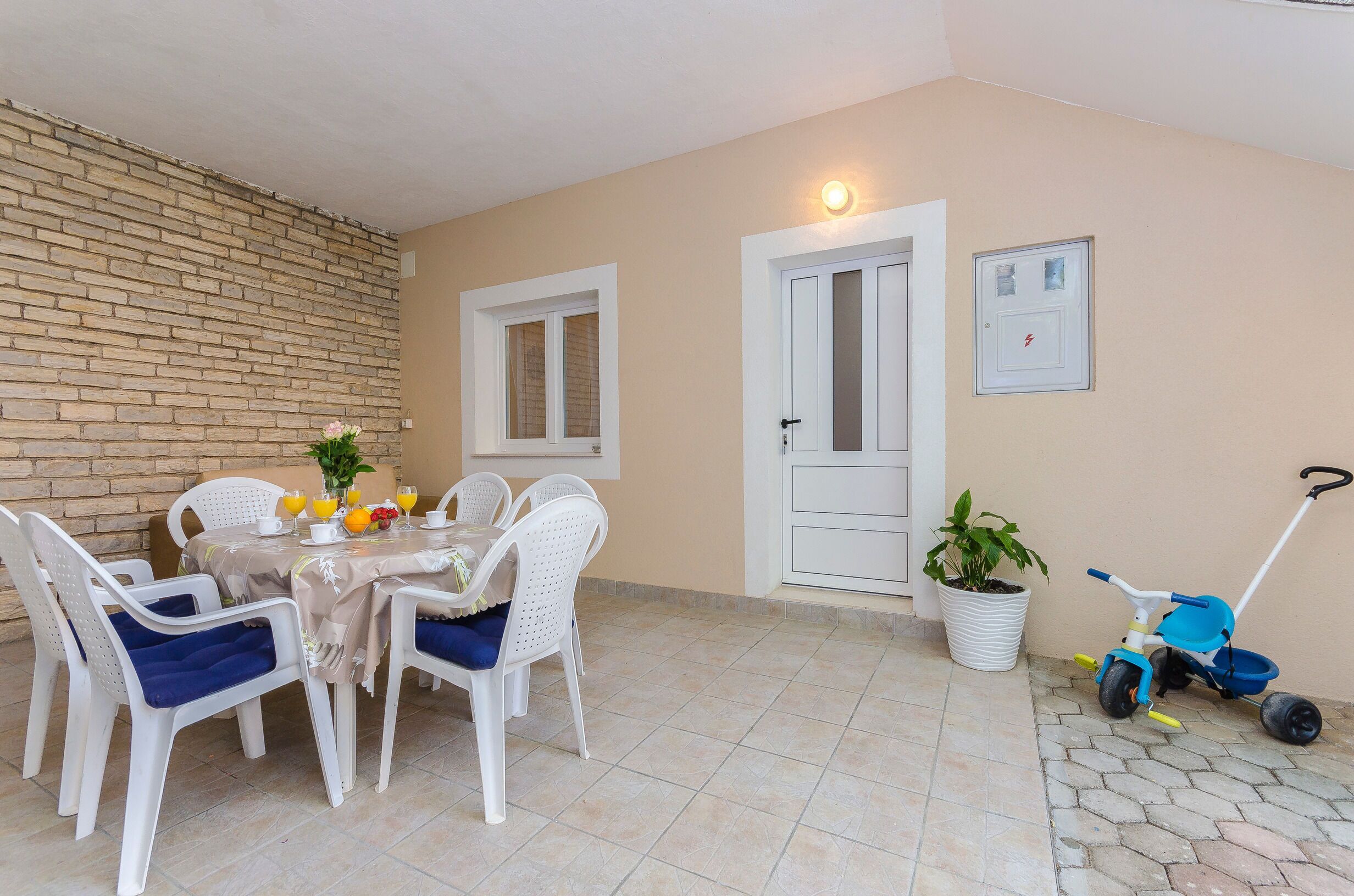 Un coin repas avec une table dressée pour quatre personnes, entourée de chaises blanches dotées de coussins bleus.