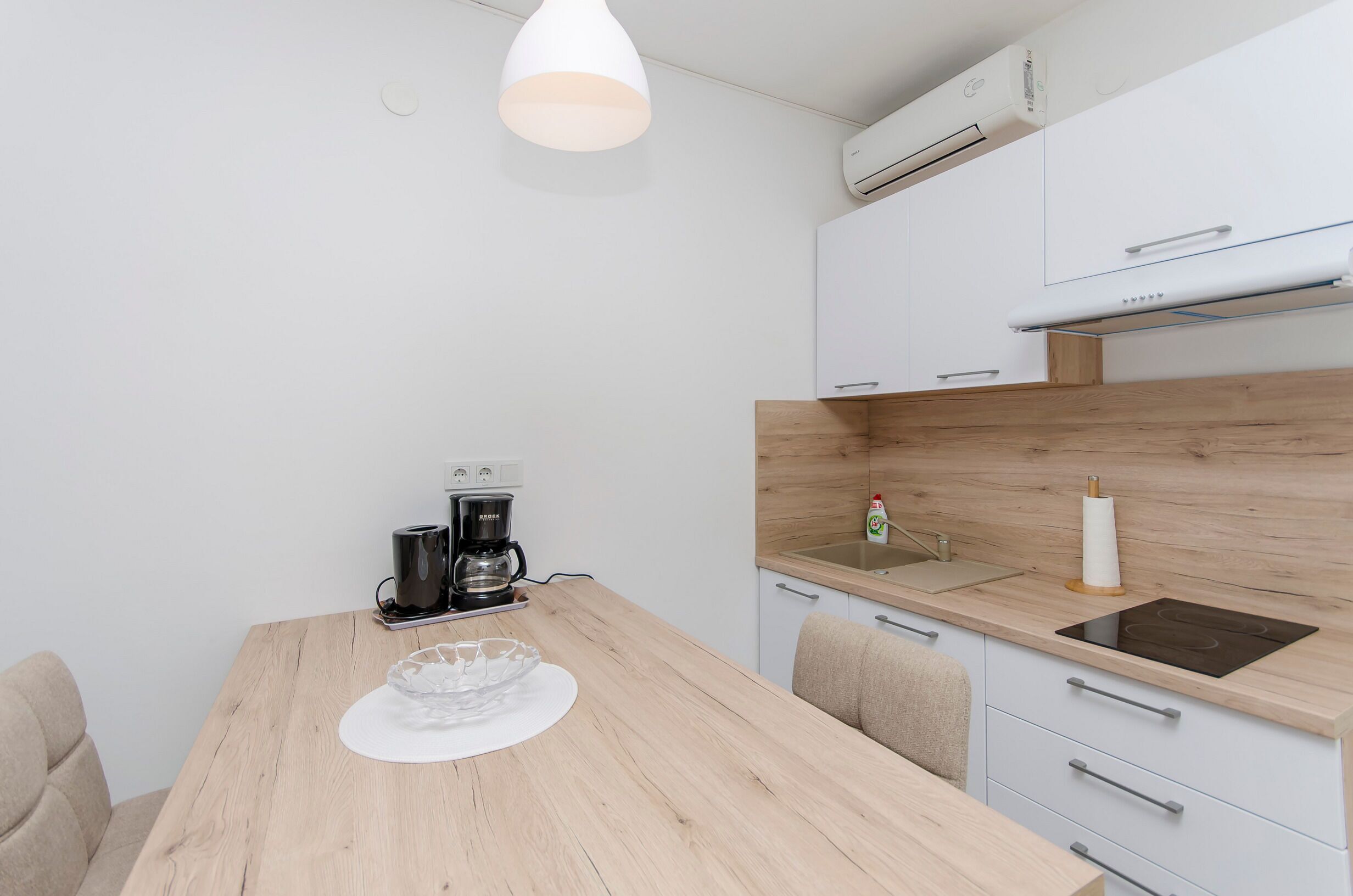 Una cocina compacta con encimera de madera, cafetera y lavabo.