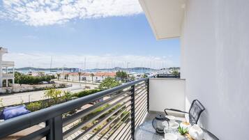 A balcony with a table set for tea, overlooking a marina with boats and buildings.