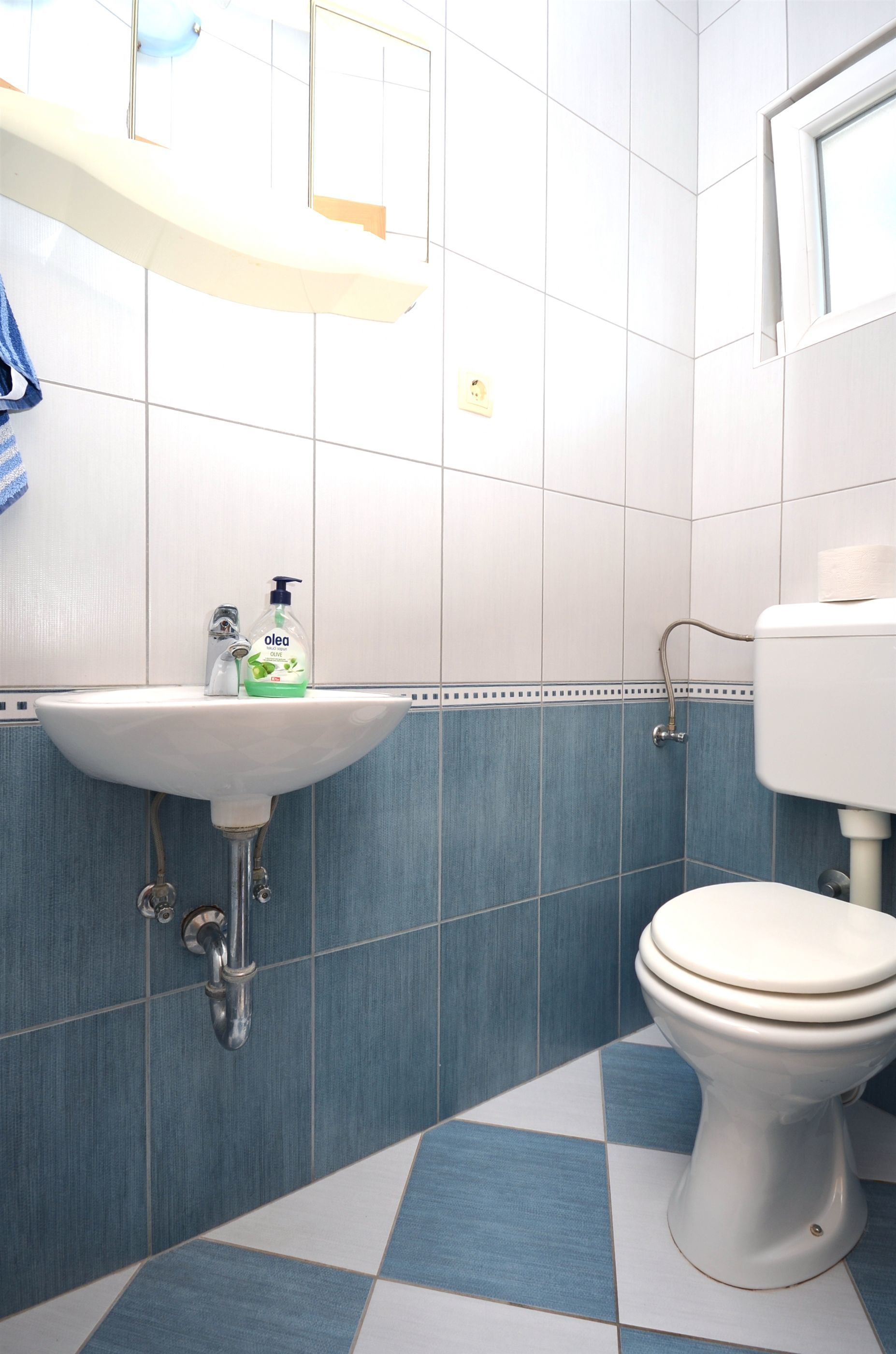 Et badeværelse med en hvid vask, blå fliser og et hvidt toilet.