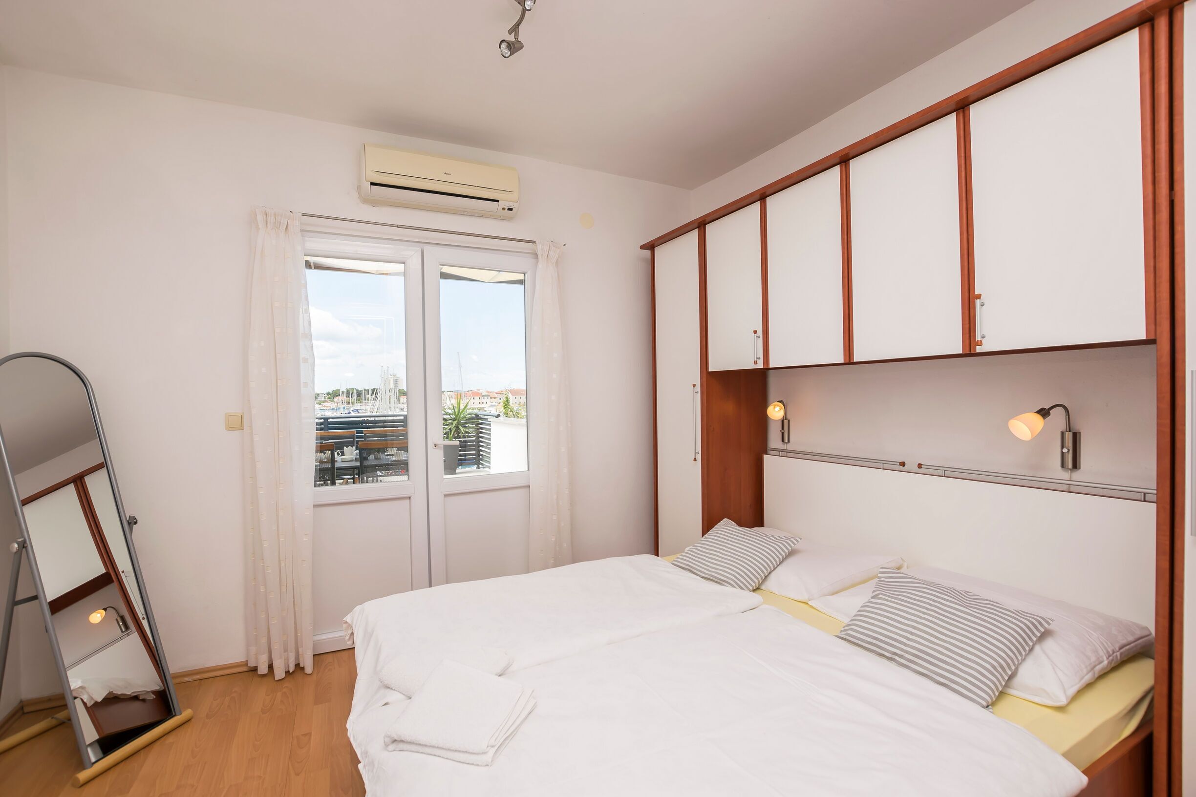 Un dormitorio con cama, armario, espejo y equipo de aire acondicionado.