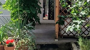 A small house with a tiled roof, a wooden door, and a small porch area with potted plants. - Apartments Marija (Razanj)