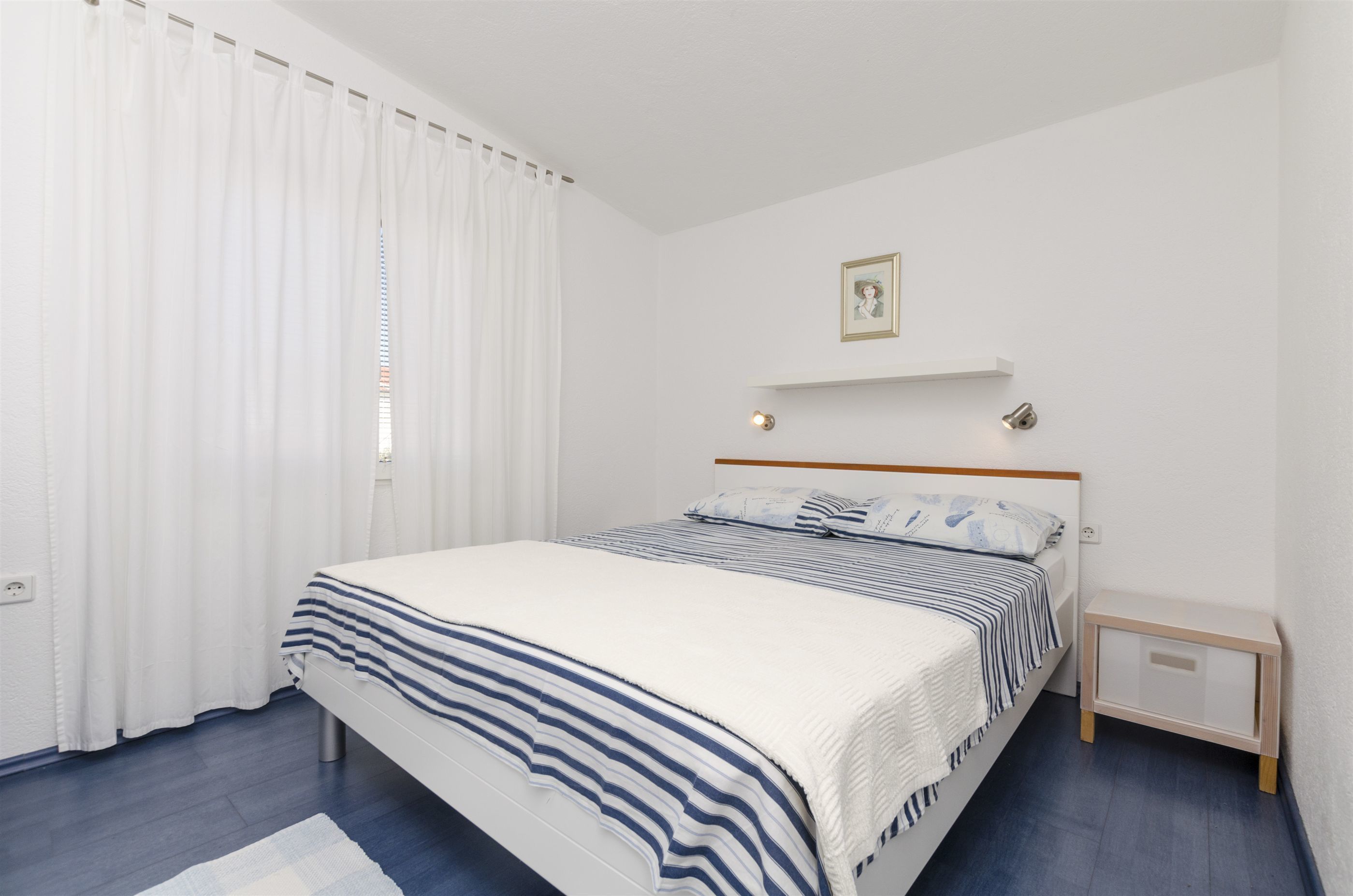 A neatly arranged bedroom with a bed, a bedside table, and a nightstand.