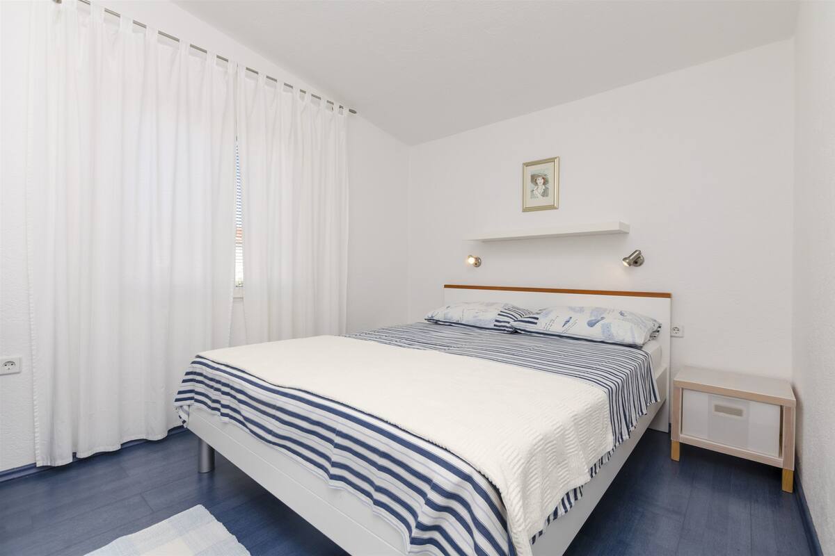A neatly arranged bedroom with a bed, a bedside table, and a nightstand.