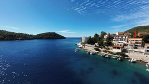 A coastal town with buildings along the waterfront, boats docked, and a clear blue sky. - Apartments Vesna (Brna)