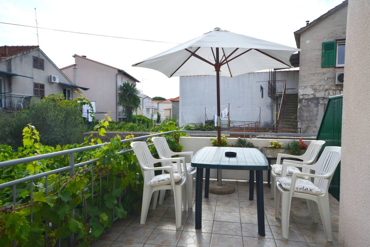 An outdoor patio with a table and chairs, an umbrella, and a railing.