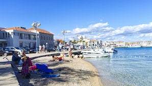 Μια παραλία με καθαρά νερά, κόσμο που χαλαρώνει και βάρκες αγκυροβολημένες.