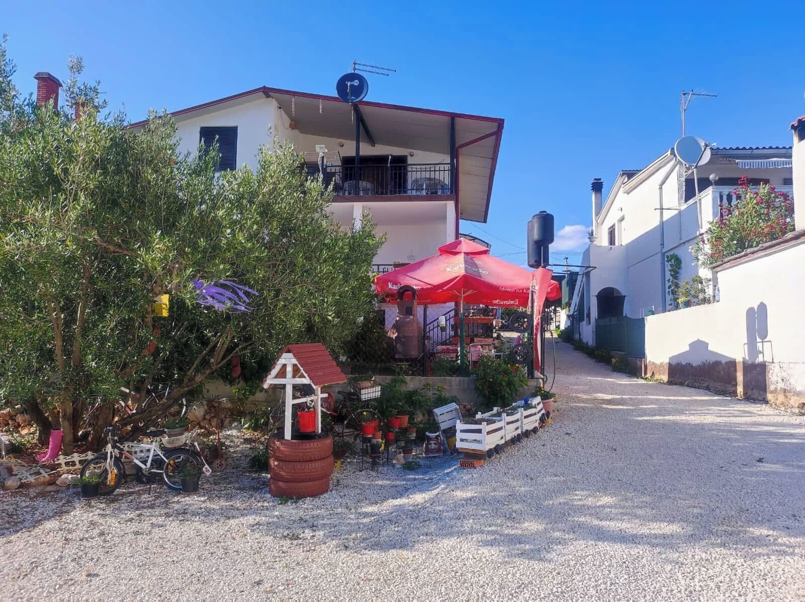 Une rue pittoresque avec un bâtiment doté d’un balcon et d’un parasol rouge.