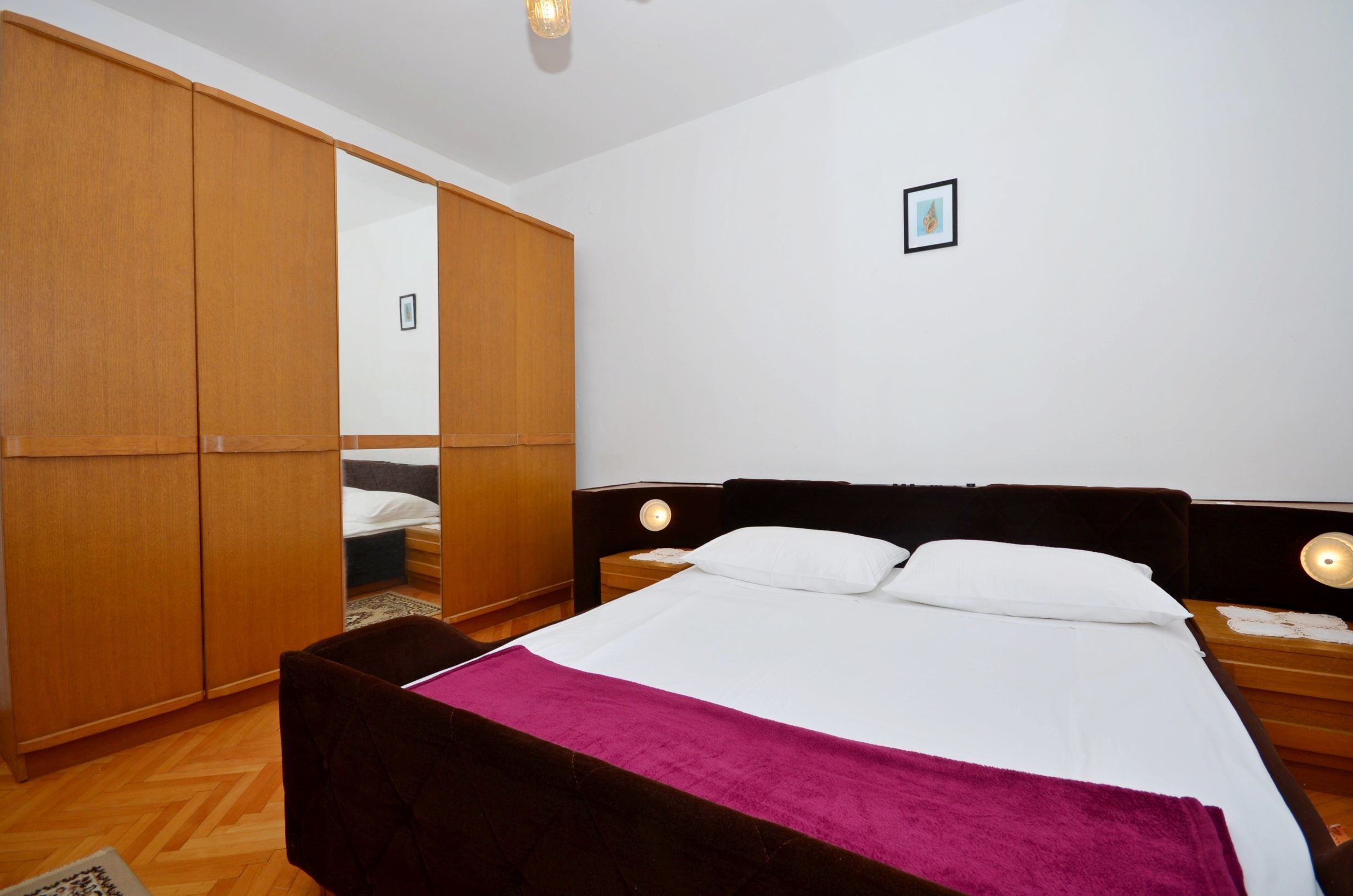 Ein Schlafzimmer mit einem Bett, einem Holzschrank, Nachttischen und einem Beistelltisch.