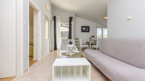 Een moderne woonkamer met een witte salontafel, een grijze bank en een eethoek met een tafel en stoelen.