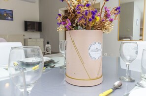 A table with a pink vase containing dried flowers, clear glasses, and cutlery. - Apartments Manda (Vodice)