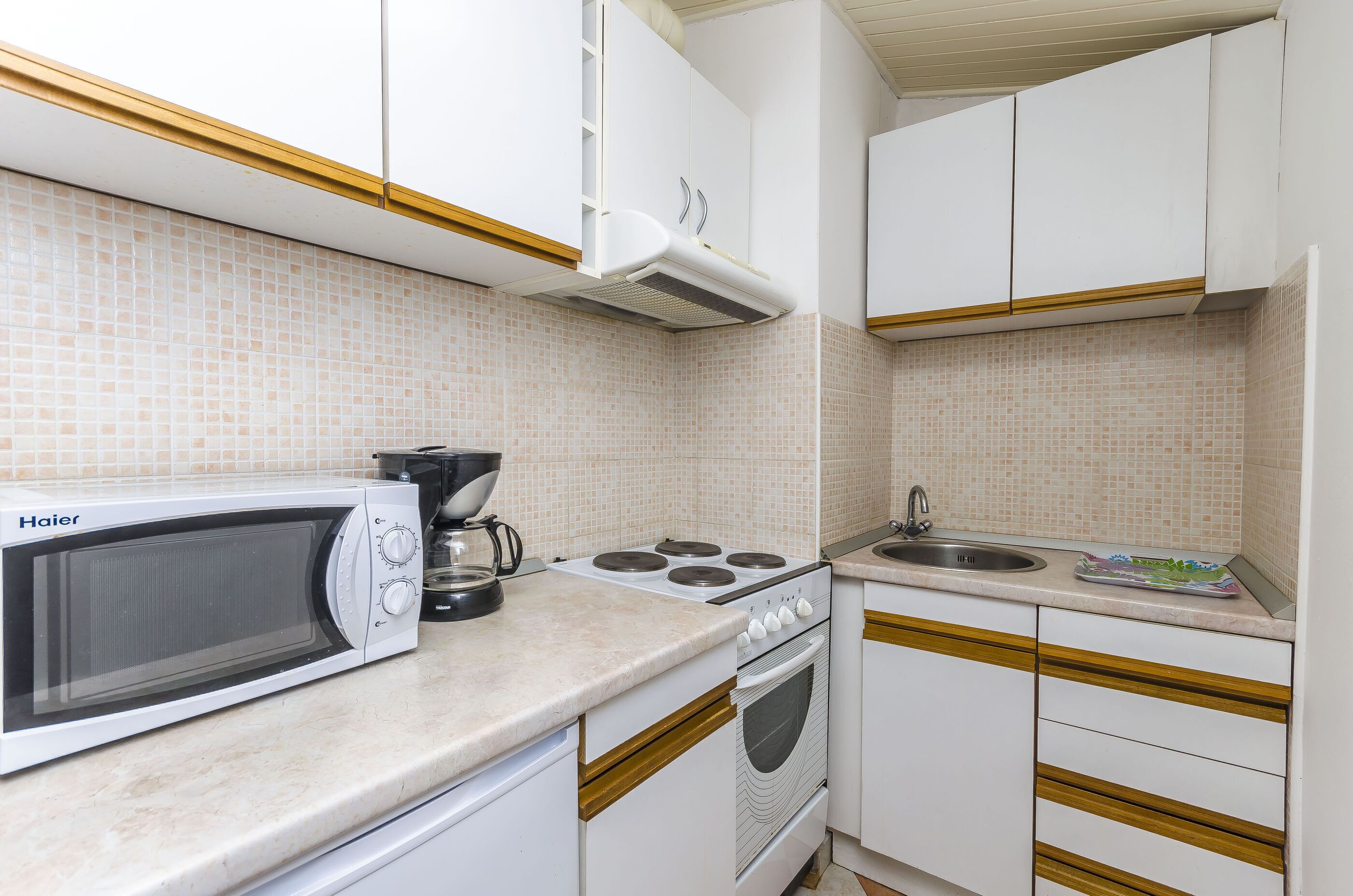 A compact kitchen with a microwave, stove, and sink.