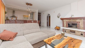 A modern living room with a sectional sofa, a wooden coffee table, and a stone fireplace with a TV.