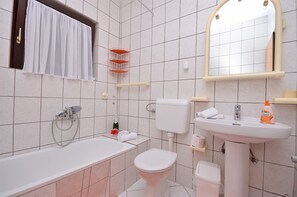 A bathroom with a bathtub, toilet, sink, and a mirror. - Apartment Tonkica (Vodice)