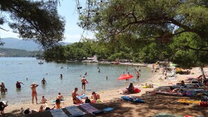 A beach with people swimming and sunbathing, umbrellas, and beach chairs. - House Lara (Vrboska)