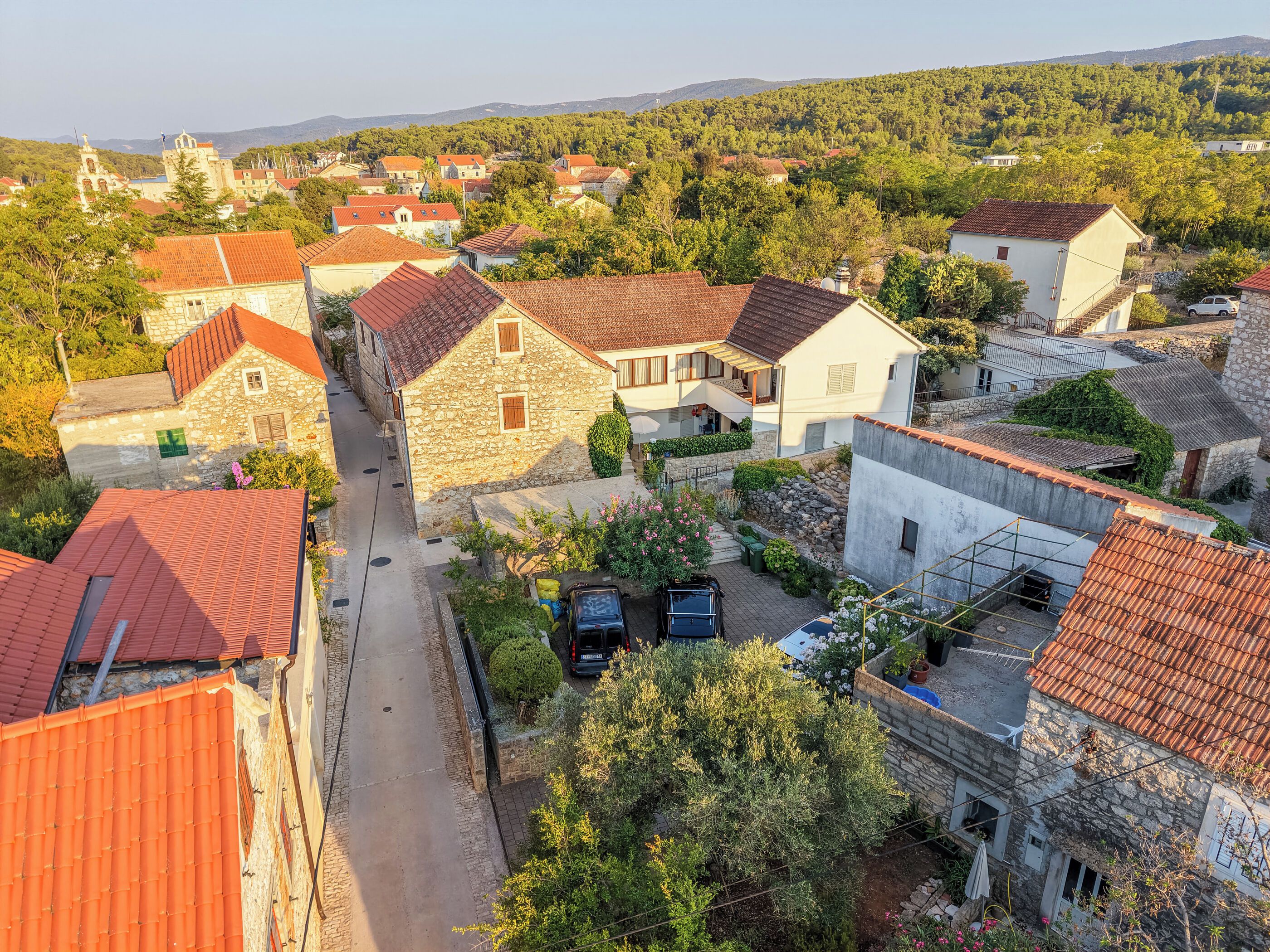 Ein Dorf mit Steinhäusern, einer schmalen Gasse und einer Bergkulisse im Hintergrund.