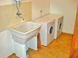 A bathroom with a sink, a washing machine, and a dryer. - House Lara (Vrboska)