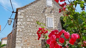 A stone building with two windows and a street lamp. - House Lara (Vrboska)