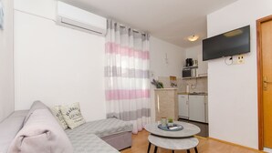 A modern living room with a sofa, a coffee table, and a TV mounted on the wall. - Apartments Cosic (Igrane)