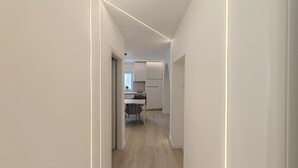 A modern, minimalist hallway with a kitchen area visible at the end. - Apartments Mateo (Vodice)
