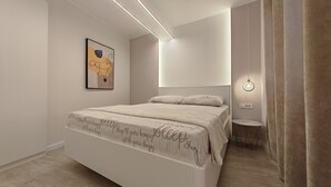 A modern bedroom with a large bed, a bedside table, and a wall-mounted light fixture. - Apartments Mateo (Vodice)