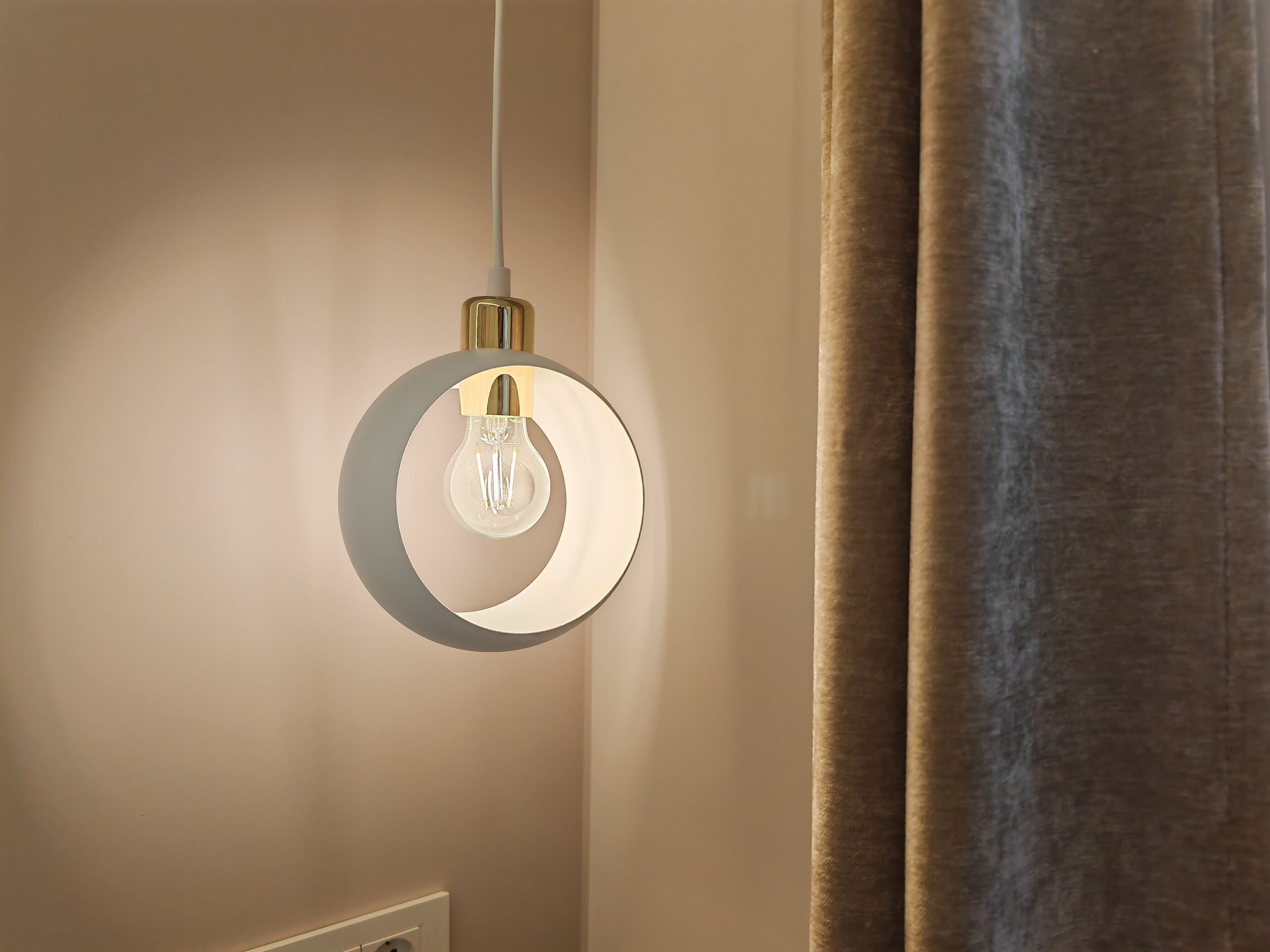 A modern light fixture with a circular design and a visible power cord.
