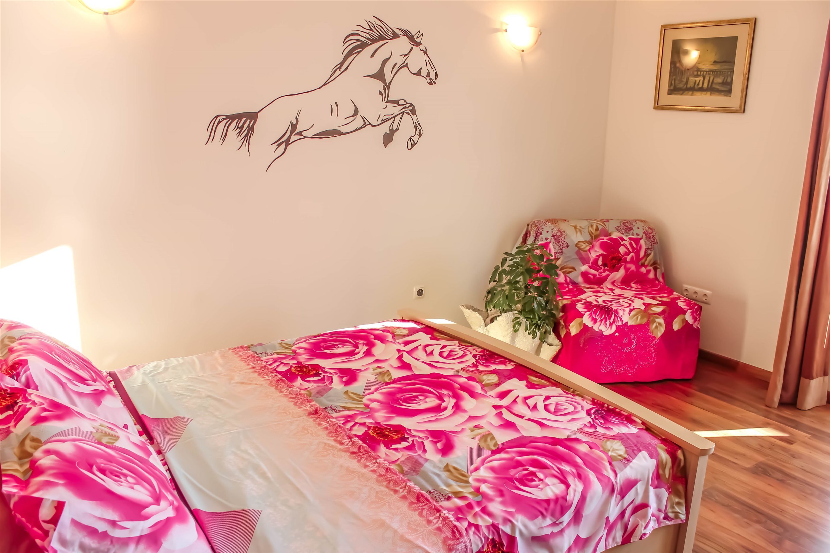 A bedroom with a bed, a chair, a wall decal, and a framed picture.