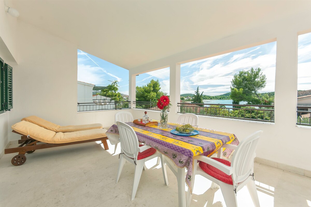 A balcony with a table, chairs, and a sun lounger.