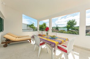 A balcony with a table, chairs, and a sun lounger.