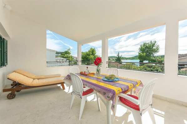 A balcony with a table, chairs, and a sun lounger.