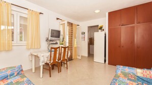 A compact living space with a dining area, a television, a refrigerator, and a wardrobe. - Apartments Srdan (Rogoznica)