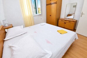 A hotel room with a bed, a nightstand, a wardrobe, and a mirror.