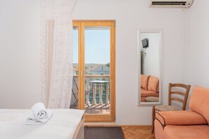 Ein Hotelzimmer mit Bett, Sofa, Spiegel und einem Balkon mit Tisch und Stühlen.