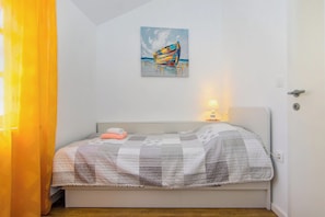 Un dormitorio con una cama, un cuadro, una mesita de noche y una lámpara.