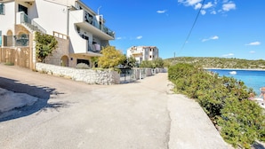 A residential street with modern houses, a clear blue sky, and a view of the sea. - Apartments Sanda (Kanica)