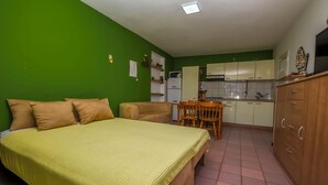 A bedroom with a bed, a chair, and a small kitchenette with cabinets and a microwave. - Apartments Sanda (Kanica)