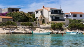 A coastal building with a balcony, a stone staircase, and a boat docked in the water. - Apartments Sanda (Kanica)