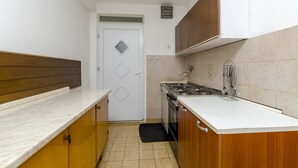 A compact kitchen with a stove, sink, and wooden cabinets. - Apartments Miodrag (Stupin Celine)
