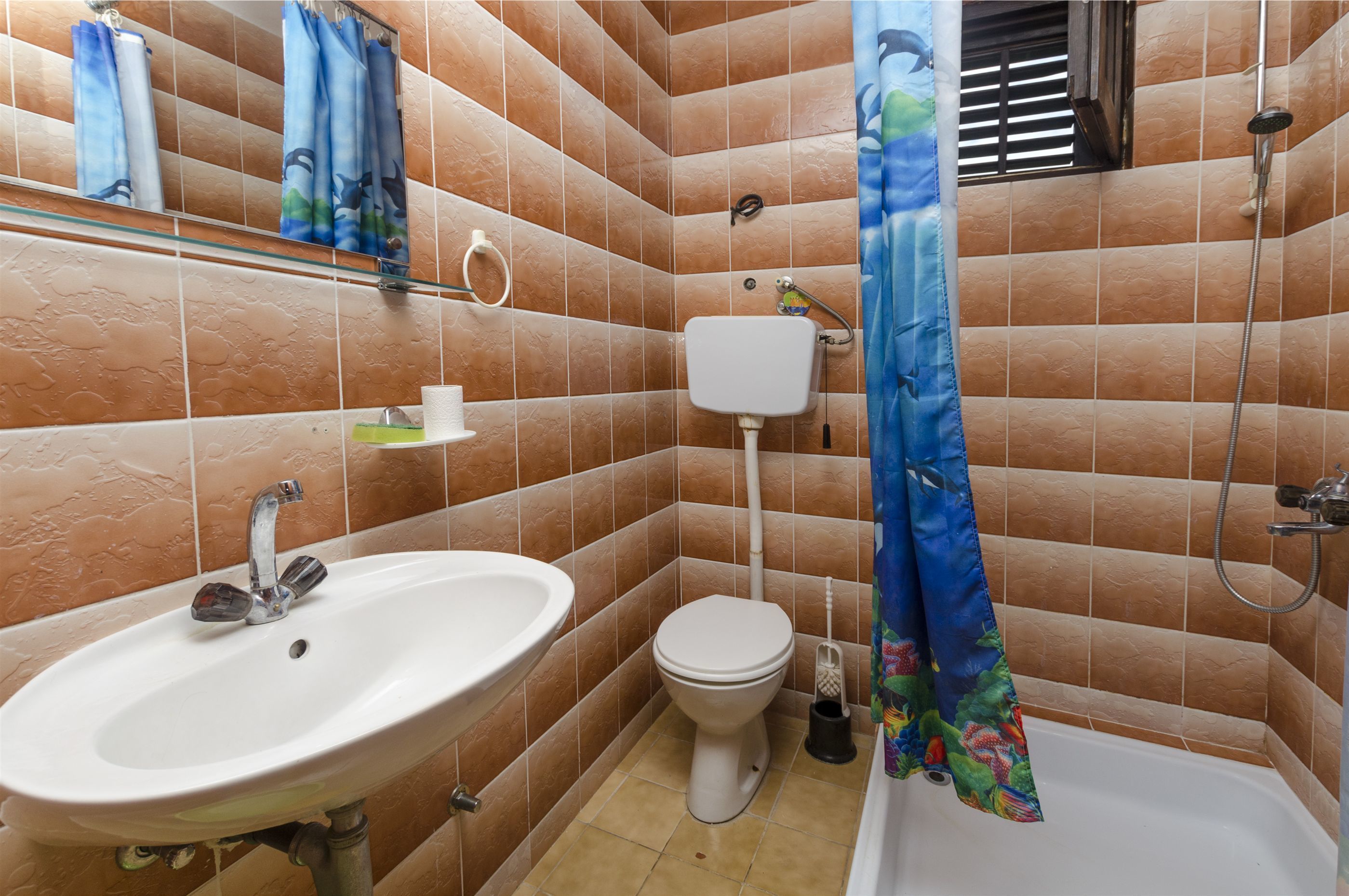 A bathroom with a sink, toilet, shower, and a mirror.