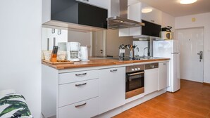 A modern kitchen with white cabinetry, stainless steel appliances, and a wooden countertop. - Apartments Sanja (Okrug Gornji)