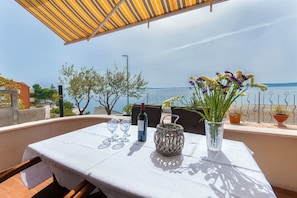 An outdoor dining area with a table set for two, a bottle of wine, and a vase with flowers.