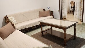 A living room with a sofa, a coffee table, and a dining area with a chair and table. - Apartments Pavlina (Starigrad - Paklenica)