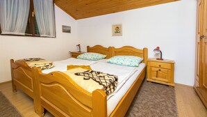 A wooden bed with a headboard, two bedside tables, and a window with curtains. - Apartments Pavlina (Starigrad - Paklenica)