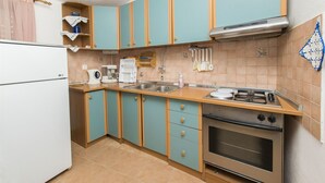 A kitchen with teal cabinets, a white refrigerator, a stove, and a sink. - Apartments Pavlina (Starigrad - Paklenica)