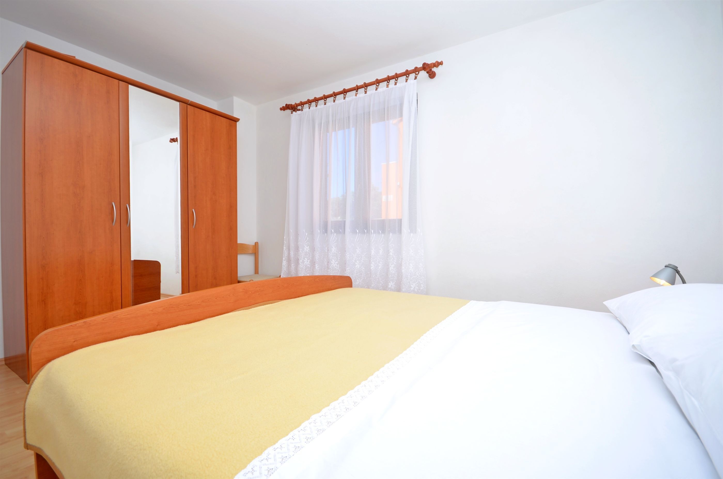 A bedroom with a bed, a wardrobe, and a window with curtains.