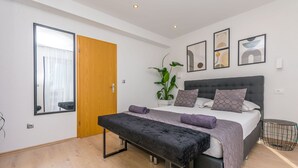 A modern bedroom with a bed, bench, and a large mirror. - Apartments Mladen (Duce)