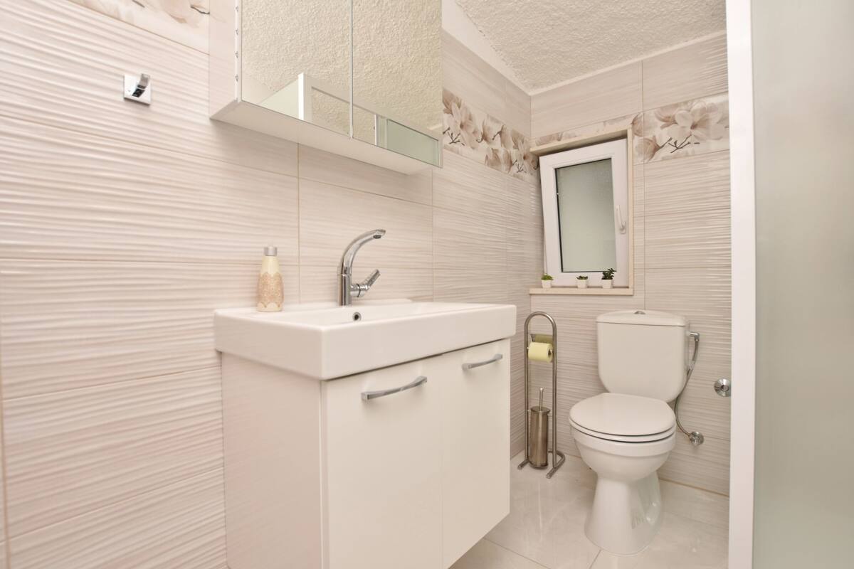 A modern bathroom with a white sink, mirror, and toilet.