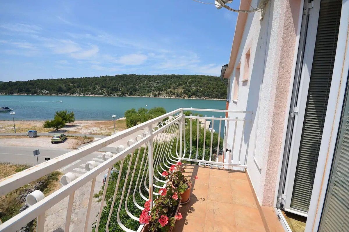 Un balcone con vista su un lago, una strada e un'auto parcheggiata.