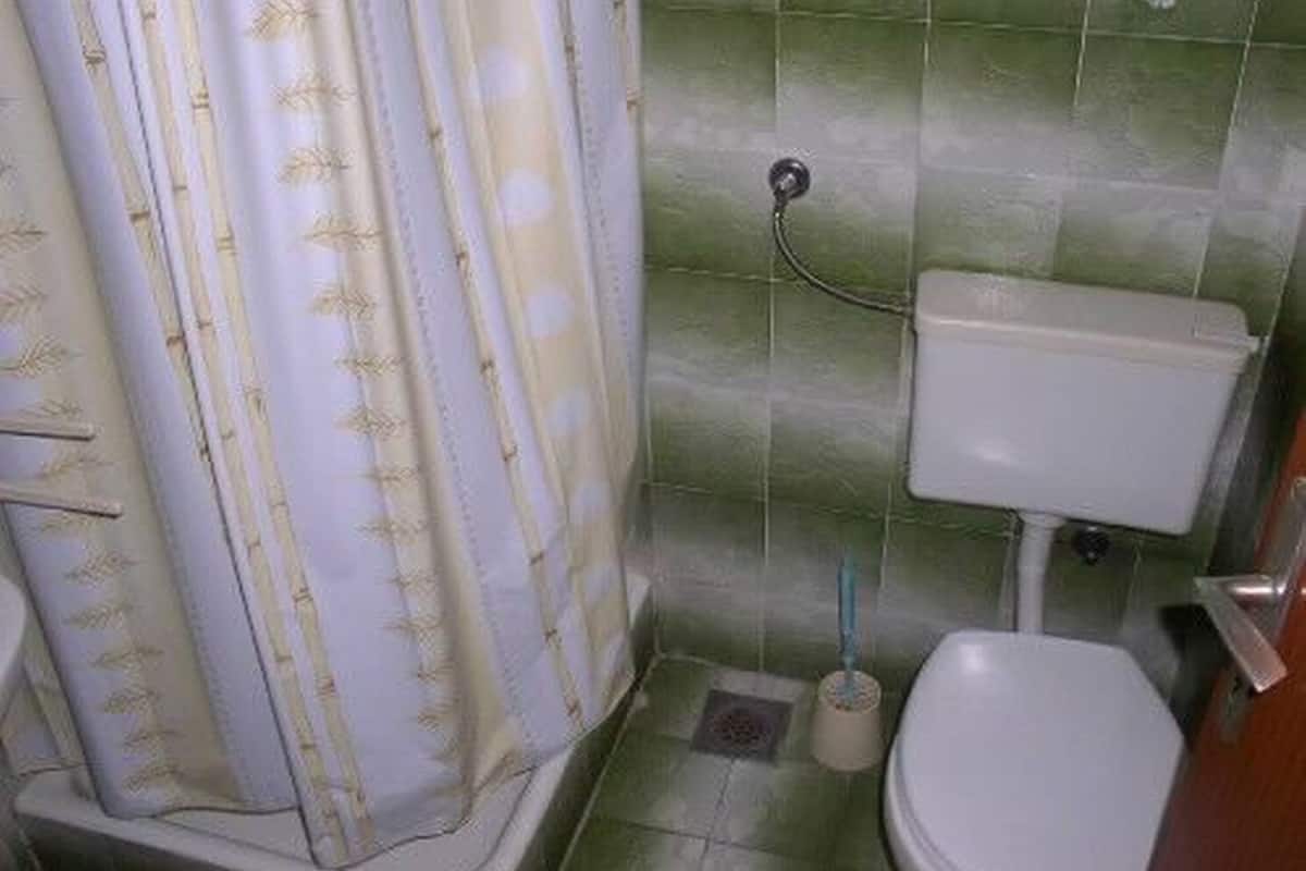 Un bagno con il water, una tenda per la doccia e pareti piastrellate.